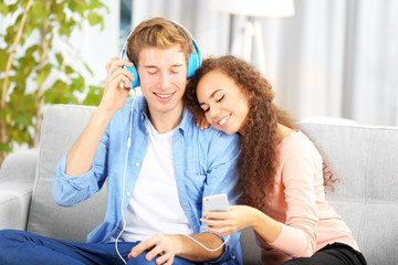 Teenager couple listening to music with mobile phone on a sofa