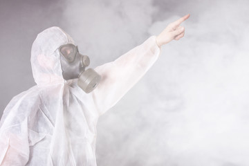 Mann im Schutzanzug und Gasmaske zeigt mit ausgestrecktem Arm 