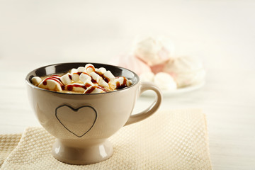 Mug of hot chocolate with marshmallows, on light wooden background