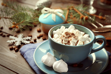 Mug of hot chocolate with marshmallows, fir tree branch on wooden background