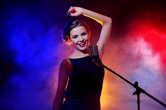 Young beautiful woman singing in colourful smoke, close up
