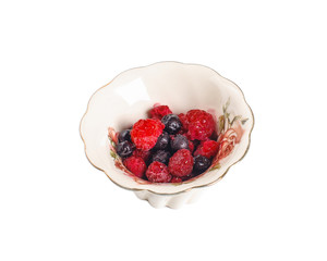 Mix of blueberries and raspberries in a ceramic bowl. Isolated on white