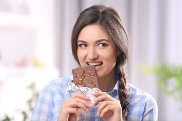 Portrait of beautiful young brunette with chocolate in the room , close up