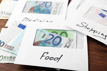 Distribution of money, financial planning, euro in envelopes, on wooden table background