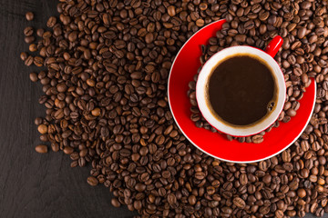 A red cup of coffee bean on the coffee beans background. Top view