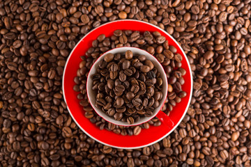 A red cup of coffee bean on the coffee beans background. Top view