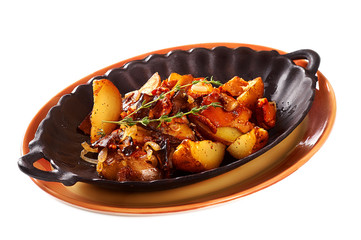 Fried potatoes with mushrooms on a metal frying pan. Isolated on white
