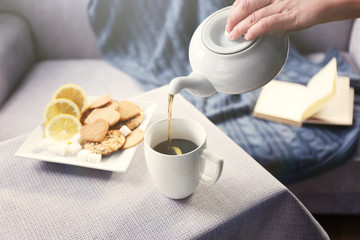 Woman pouring tea in mug from kettle