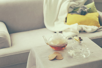 Tea cup and kettle on the table beside sofa