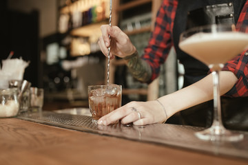 Barista woman making an alcohol cocktail at the bar - cropped photo