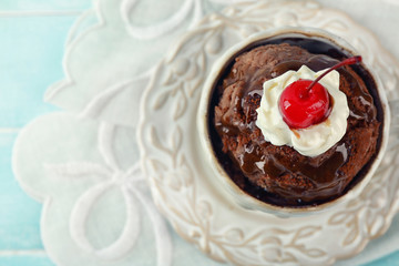 Chocolate mug cake with cream and cherry on blue wooden background, top view