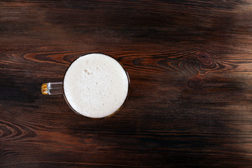Fototapeta na wymiar Glass of beer on wooden table, top view