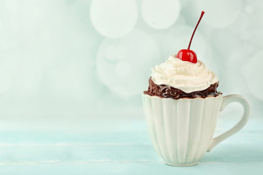 Chocolate mug cake with cream and cherry on a table