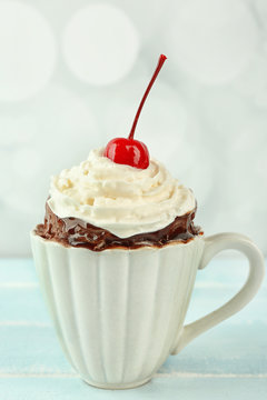 Chocolate mug cake with cream and cherry on a table