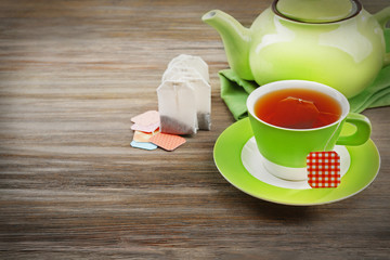 Cup of tea with tea bags and teapot on wooden table background