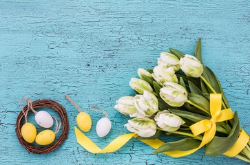 Easter background with white flowers and decorative eggs in small nest. Copy space