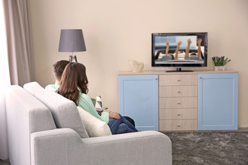 Young couple watching TV on a sofa at home