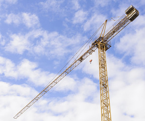 Fototapeta na wymiar Yellow Industrial Crane Against Blue Sky