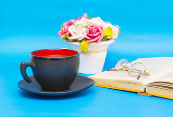 Cup of coffee with book isolated on blue background