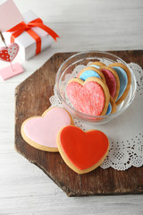 Valentine heart cookies in glass bowl with present box on wooden background