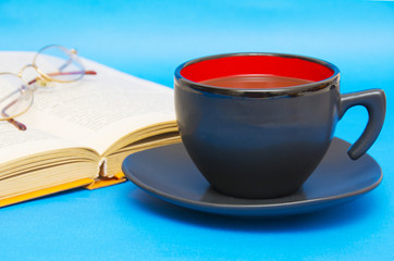 Cup of coffee with book isolated on blue background