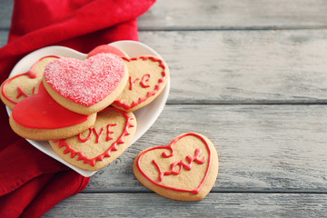 Fototapeta na wymiar Assortment of love cookies with red cloth on grey wooden table background