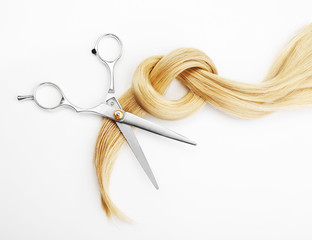 Hairdresser's scissors with strand of blonde hair, isolated on white