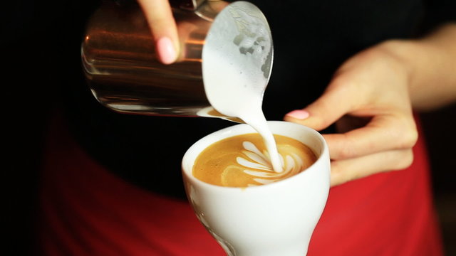 hands of barista making latte or cappuccino coffee pouring milk making latte art.