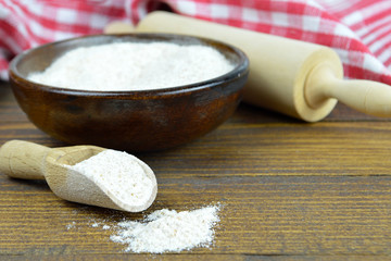Whole wheat flour in wooden bowl,wooden scoop and rolling pin on the table