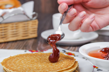 Putting strawberry jam on pancakes