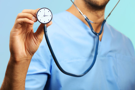 Male Doctor Holding Stethoscope With Clock