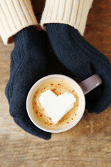 Woman hands in mittens holding a cup of coffee