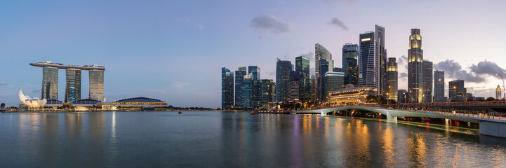 Naklejka premium Colorful Singapore business district skyline after sun set at Marina Bay. Panoramic image.