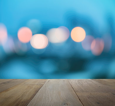 wood table top on abstract background with bokeh defocused lights and shadow from cityscape at night, vintage or retro color tone 