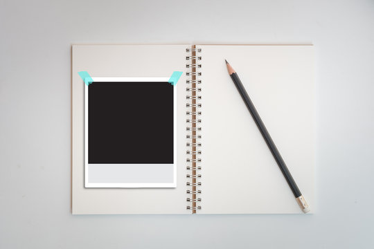 Polaroid photo frames on notebook and pencil
