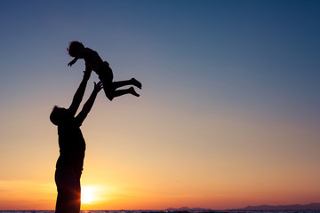 Father and son playing on the beach at the sunset time.