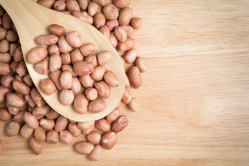 scoop of peanut on a pile of peanut on a wooden background