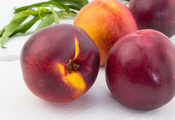 Ripe red and orange nectarines on white wood background