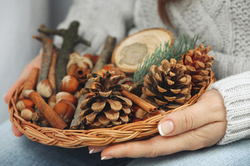 Wicker basket with Christmas decoration in woman hands, closeup