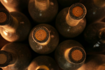 Stacks of dusty wine bottles on wooden background, upside view. Close up