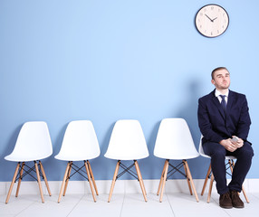 Young businessman sitting on a chair in blue hall