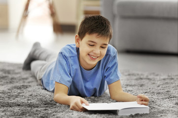 Boy reading book on a floor at home