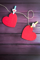 Red felt hearts are on cord against purple wooden background