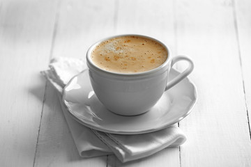 Cup of coffee with foam on wooden background