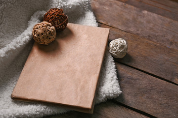 A book, decorative balls and a soft blanket on wooden background