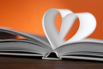 Heart from book pages on red blurred background