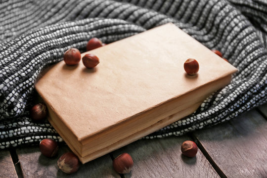 A book, hazelnuts and a woolen blanket on the floor, close-up