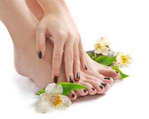 Obraz na płótnie Canvas Manicured female feet and hand with spa stones and flowers isolated on white