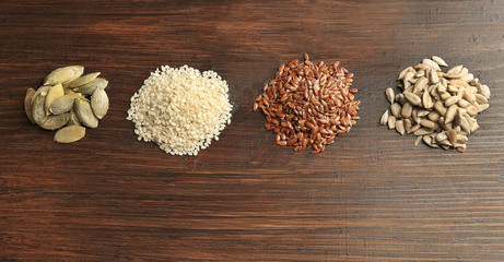 Heaps of sesame, flax, pumpkin and sunflower seeds on wooden table background, closeup
