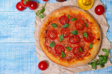 Italian cuisine. Mediterranean cuisine. Pizza Margherita with tomato topped with melted golden cheese, herbs and basil served  on old wooden table